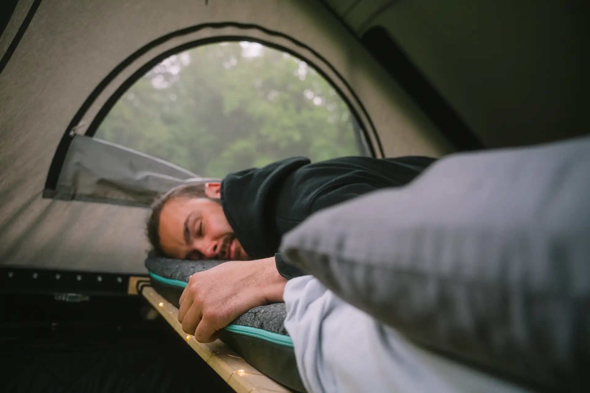 Paul liegt auf seiner Vanmade Original Matratze und einem maßgefertigtem Spannbettlaken im Aufstelldach