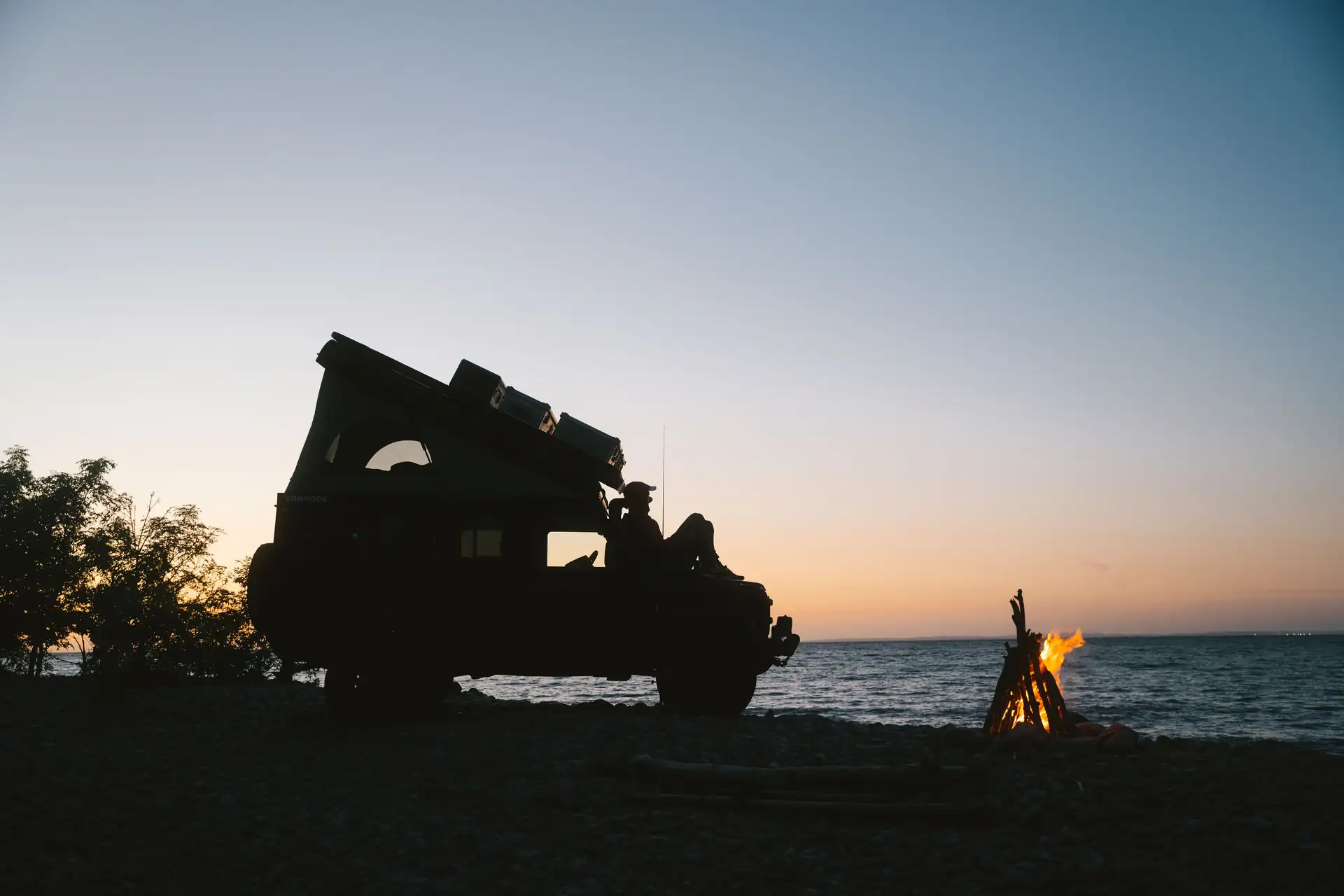 Lifestyle, Offoad Fahrzeug steht neben Lagerfeuer am Strand, Abendstimmung