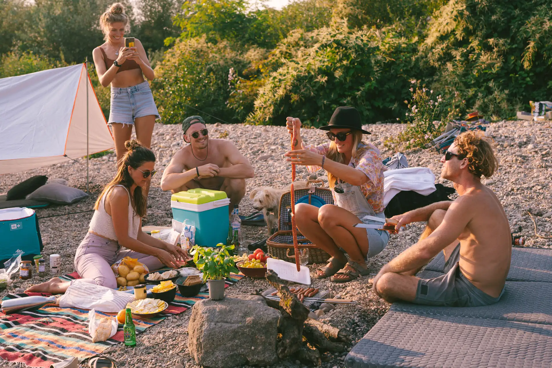 Lifestyle, 5 Freunde sitzen beisammen auf einem Kieselstrand, spass und freude, Abendstimmung